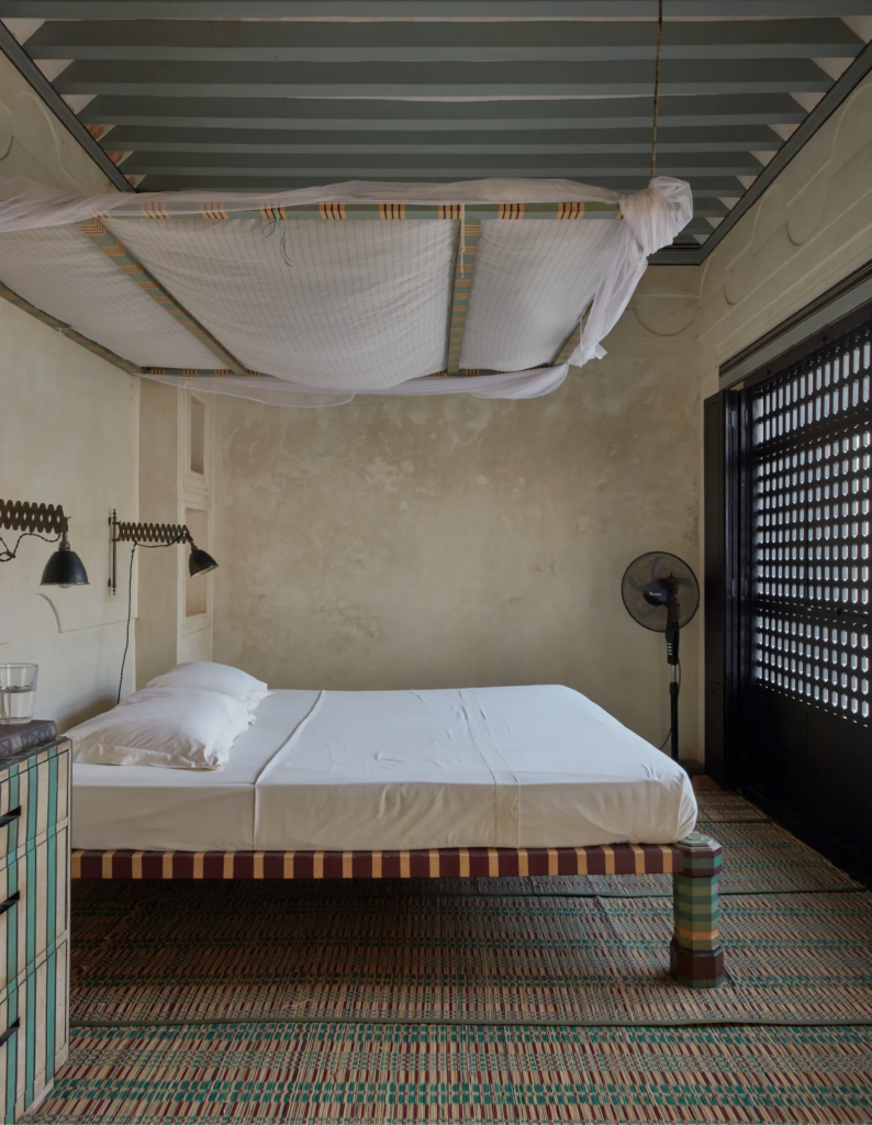 Minimalist bedroom with a suspended mosquito net and woven mats.