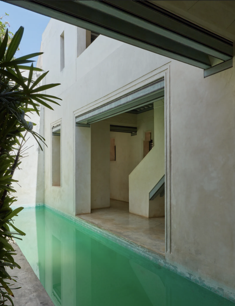 Outdoor pool with minimalist architecture and lush greenery.