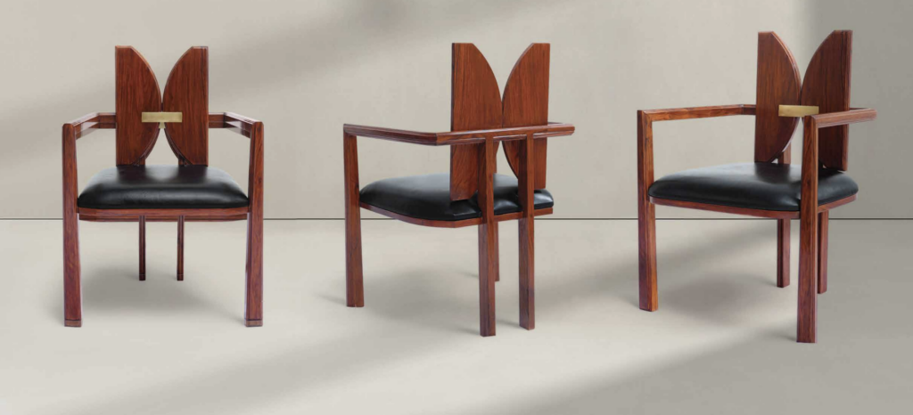 Wooden Armchairs with Butterfly-Shaped Backrest – A trio of wooden armchairs with an eye-catching butterfly-inspired backrest. The black leather seat cushion and brass accent in the center of the backrest add a luxurious touch to the modern, sculptural design.